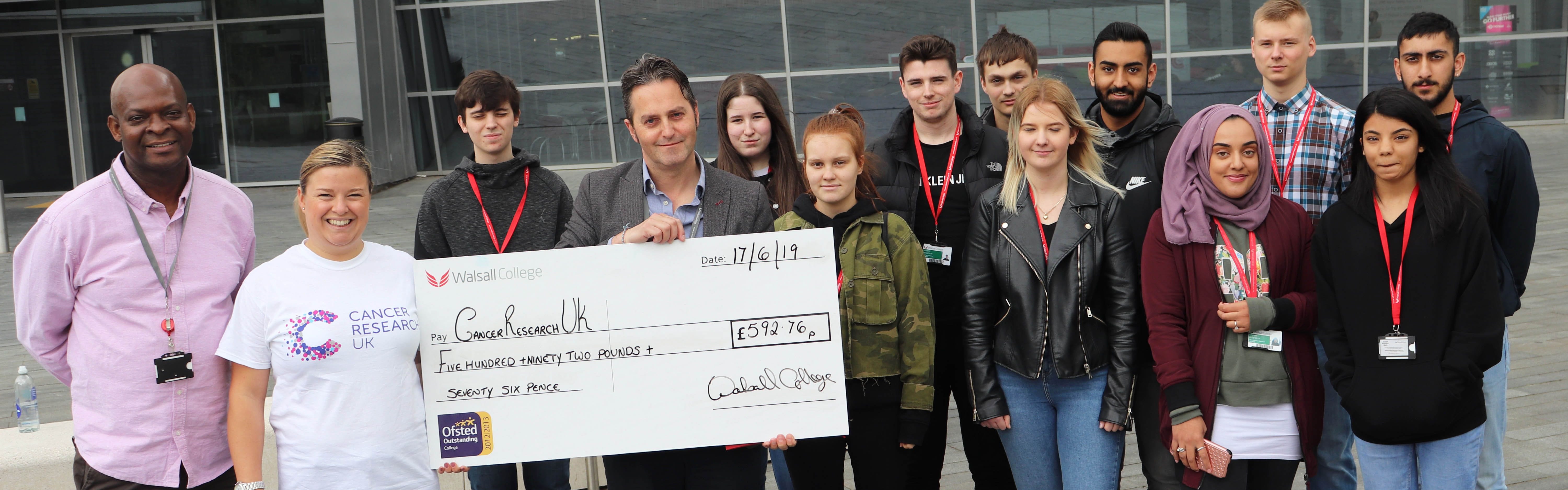 business students hold cheque with assistant principal and Smile for Joel representative facing