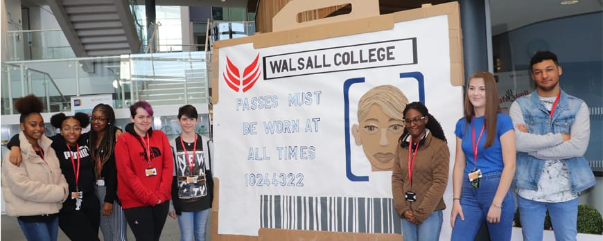 group shot of art and design students with ID card art exhbit facing