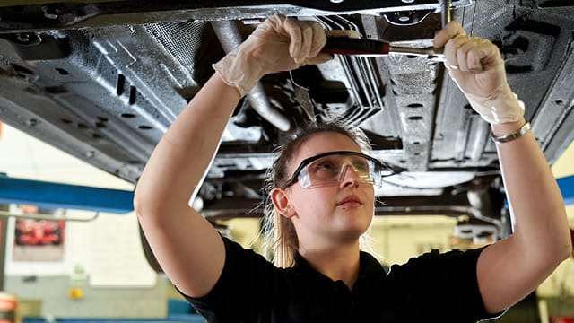 pic of female mechanic working underneath a car