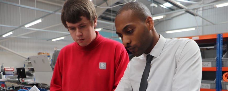 apprentice alumni examines workshop equipment with colleague