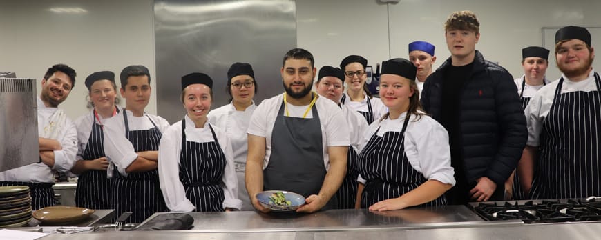 group shot of student chefs posing with industry professional facing