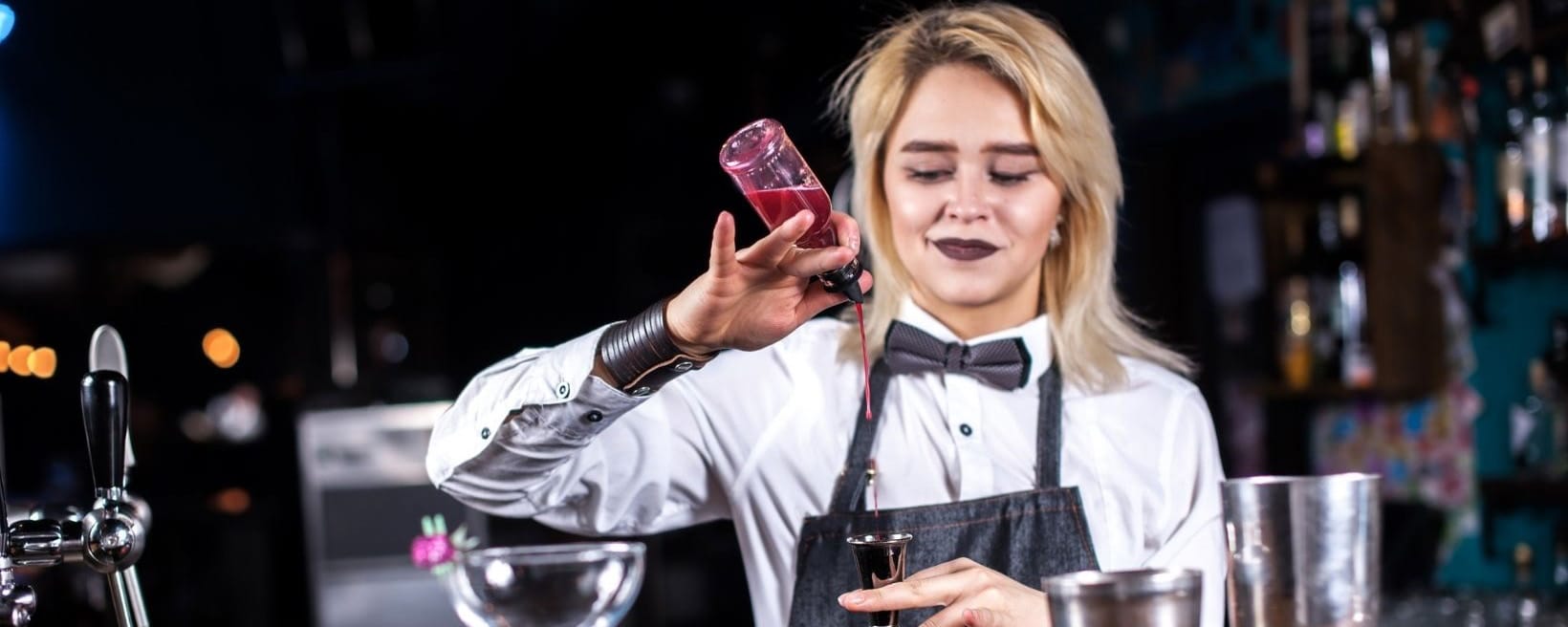 female serving staff mixes drink at bar