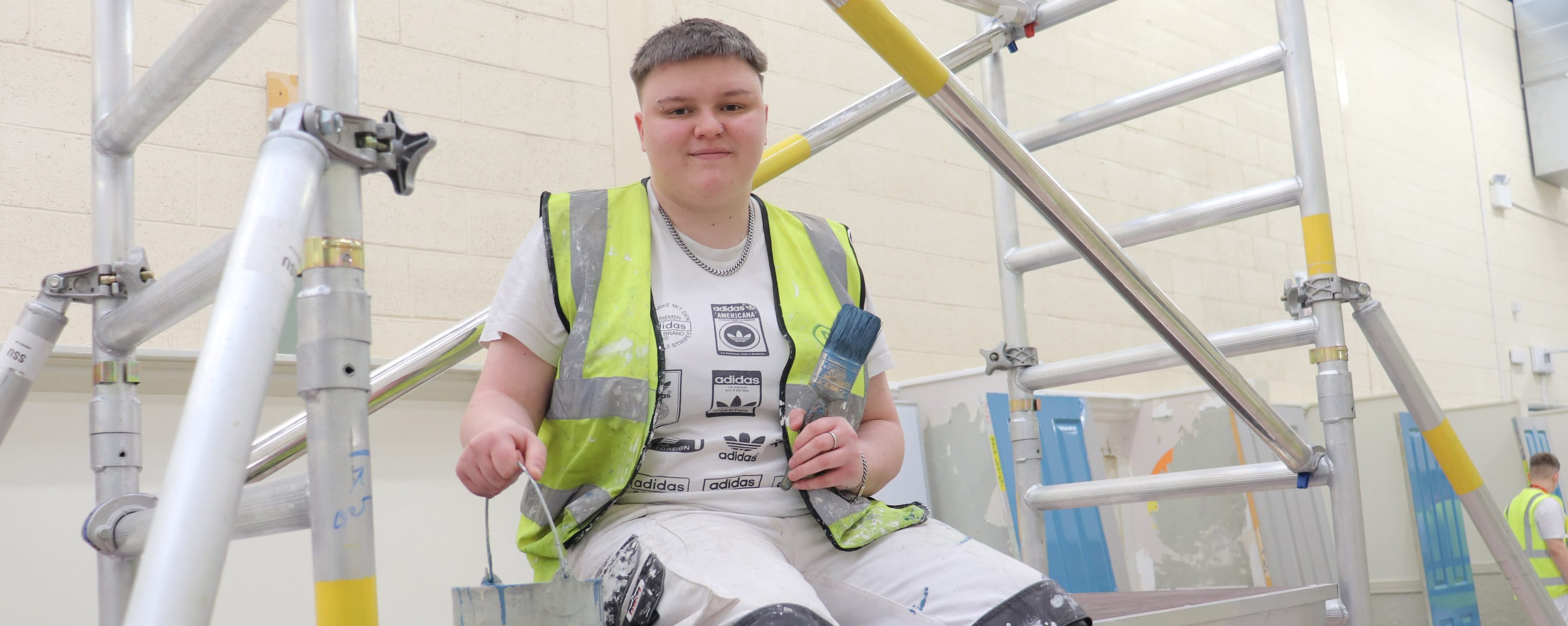 female painting and decorating apprentice sits on ladder facing