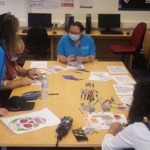 staff and learners participating in colouring activity seated at table
