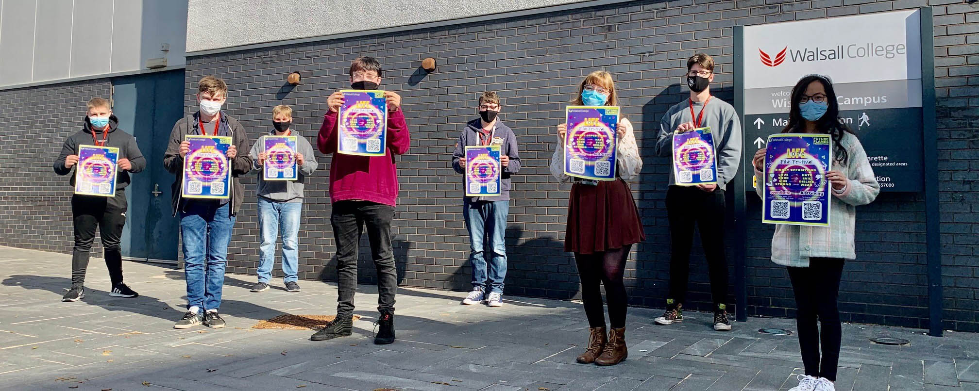 group shot of media students posing with film festival event posters