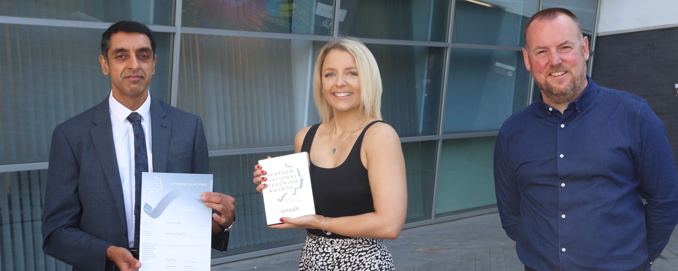 female media lecturer holds award presented by principal and Pearson representative facing