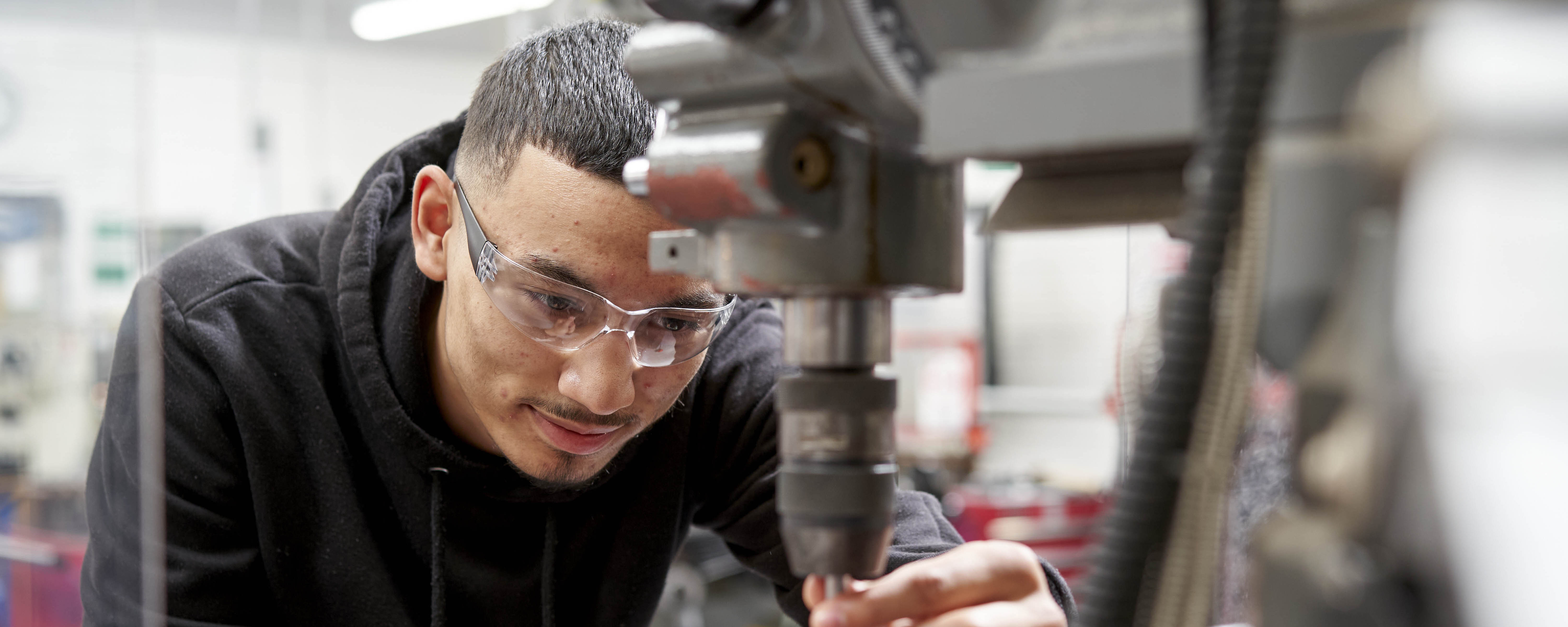 male engineering student in front of mechanical drill