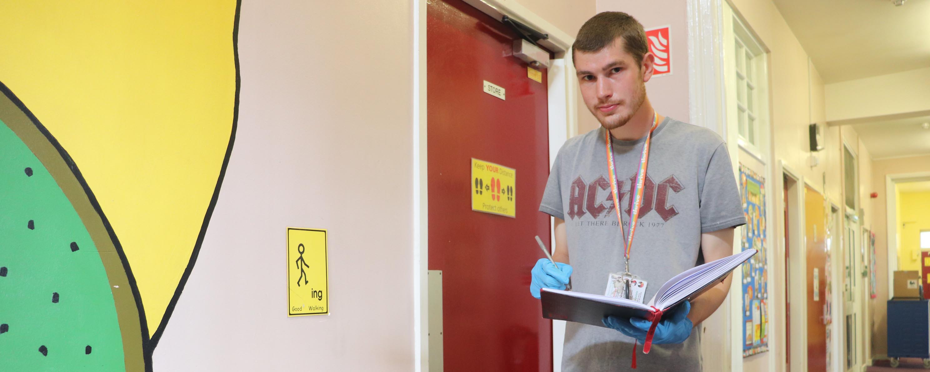 male facilities apprentice in school corridor facing