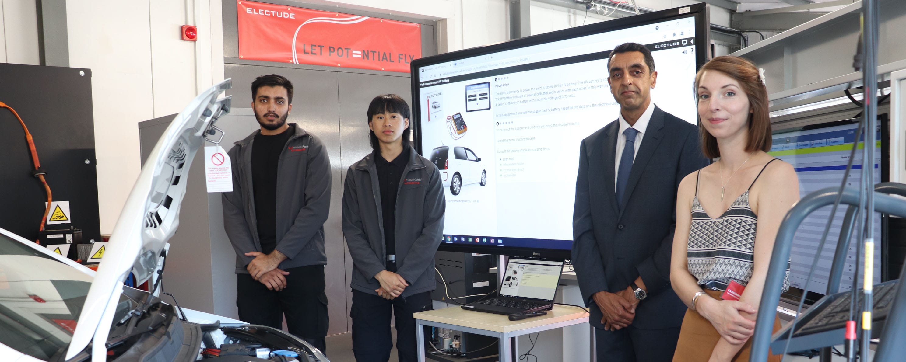 principal and automotive students stand by electric vehicle facing with Electude representative