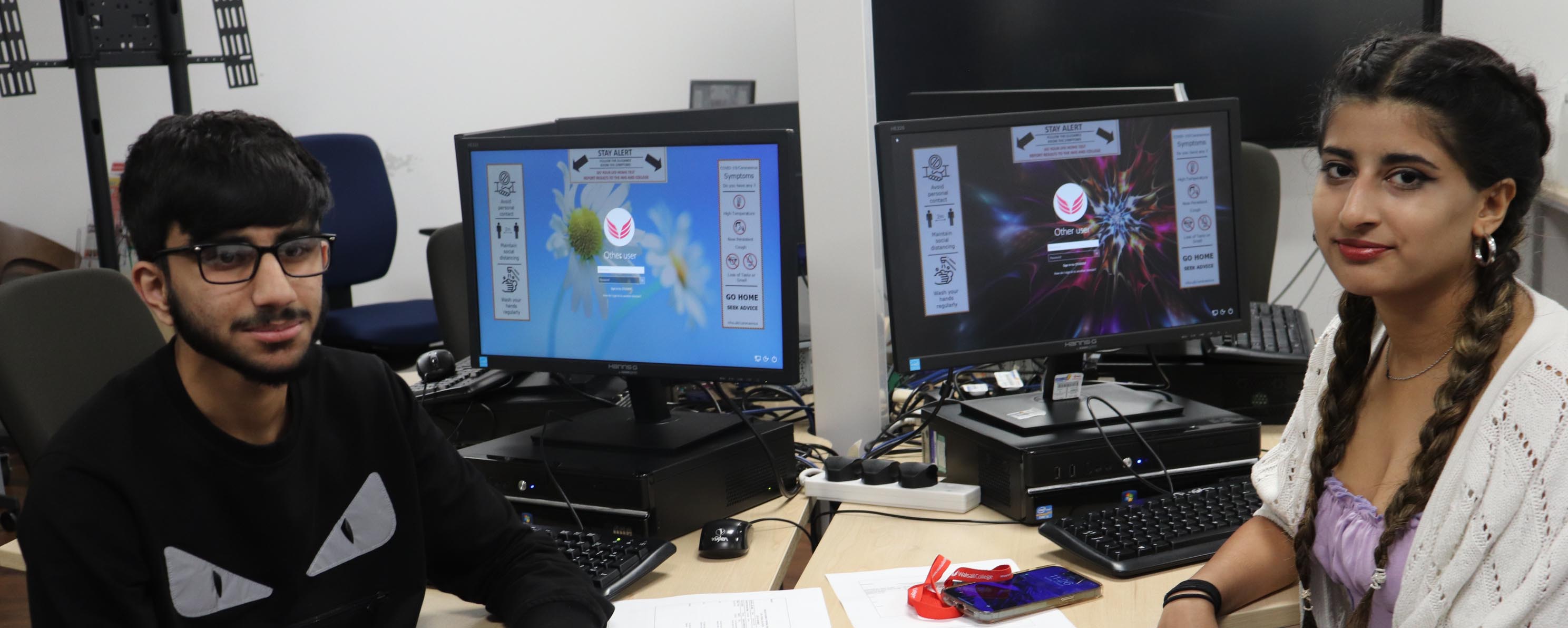 male and female computing students by desktop screens facing