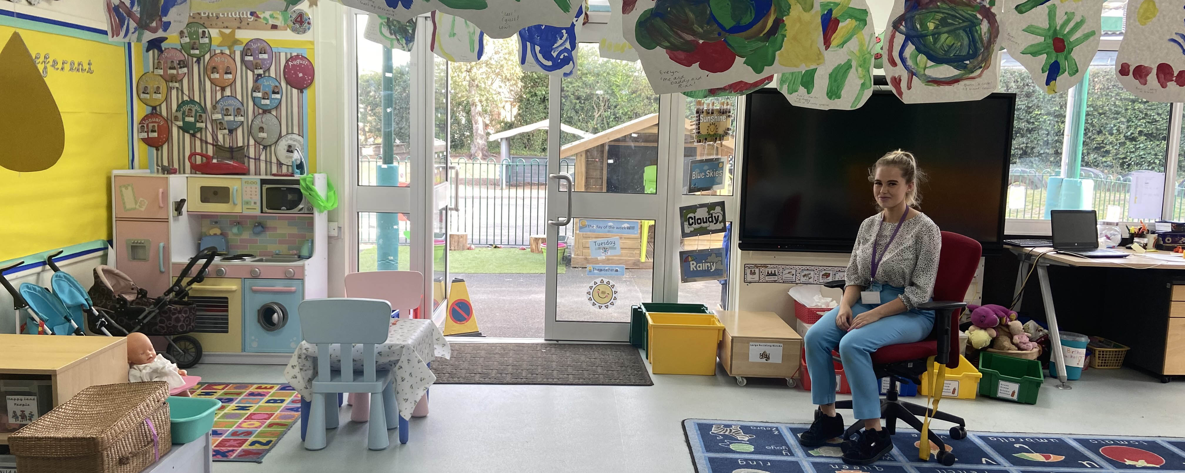 apprentice teaching assistant seated in primary school classroom facing