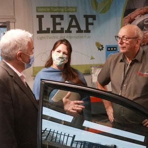 Ofqual representative in electric vehicle workshop speaking to lecturer and corporation chair