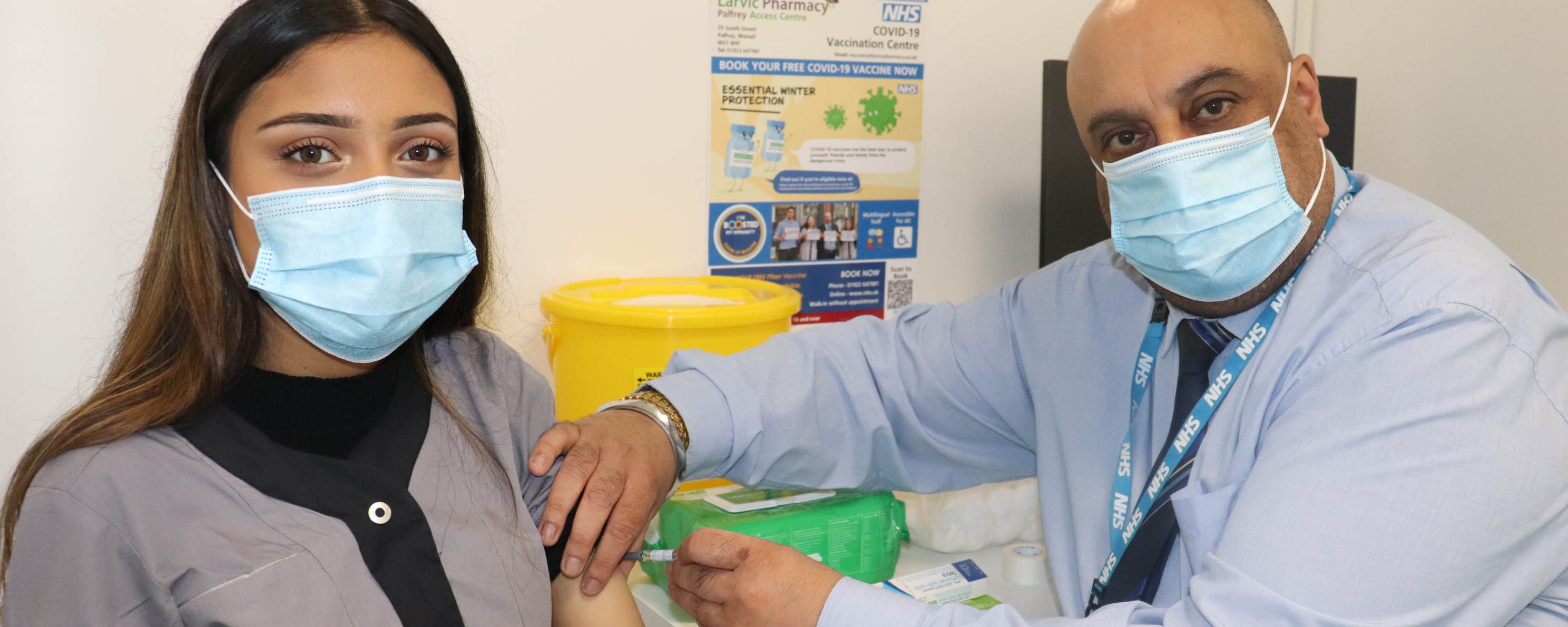apprentice pharmacy assistant receiving vaccine from pharmacist facing