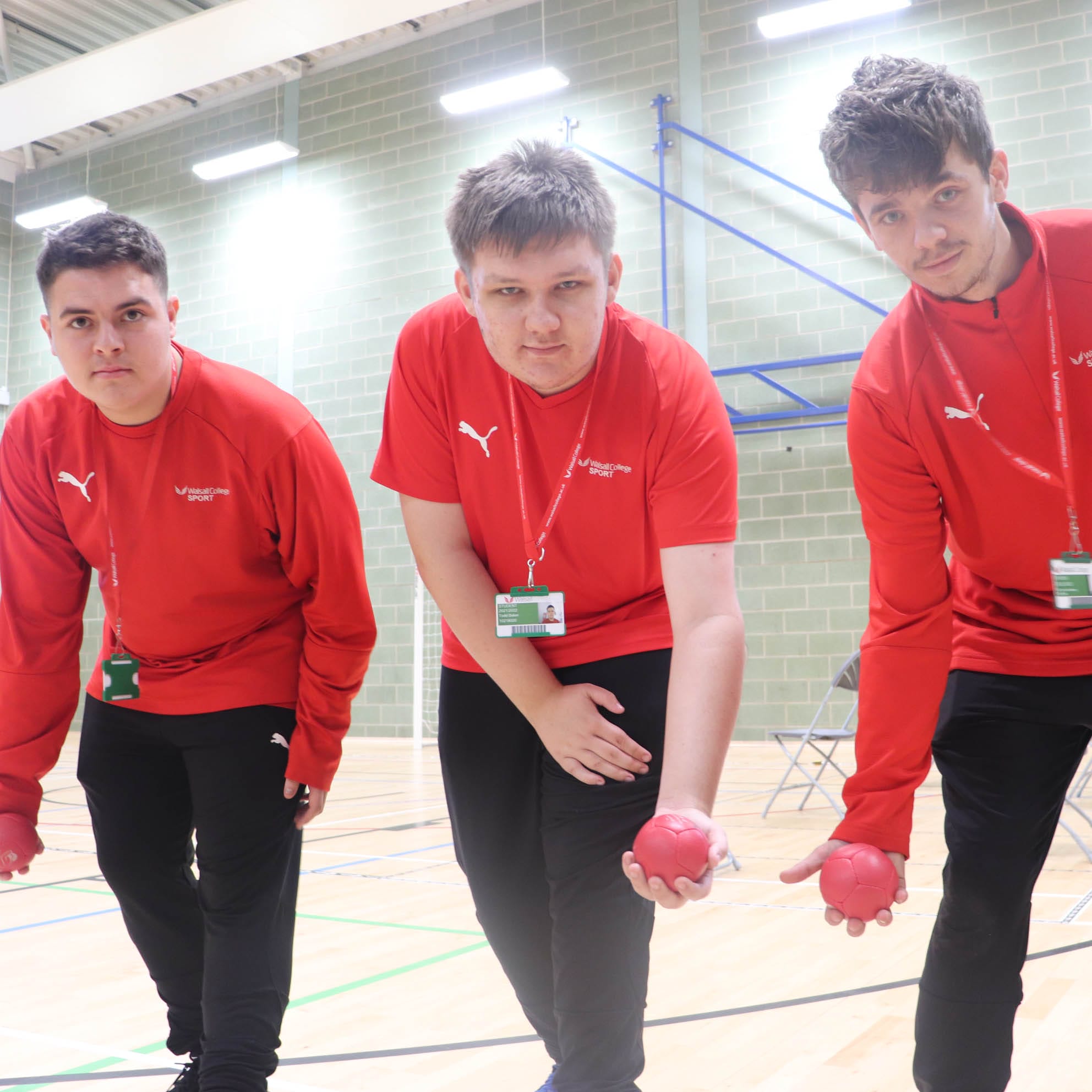 three supported learning students with boccia balls in hand facing