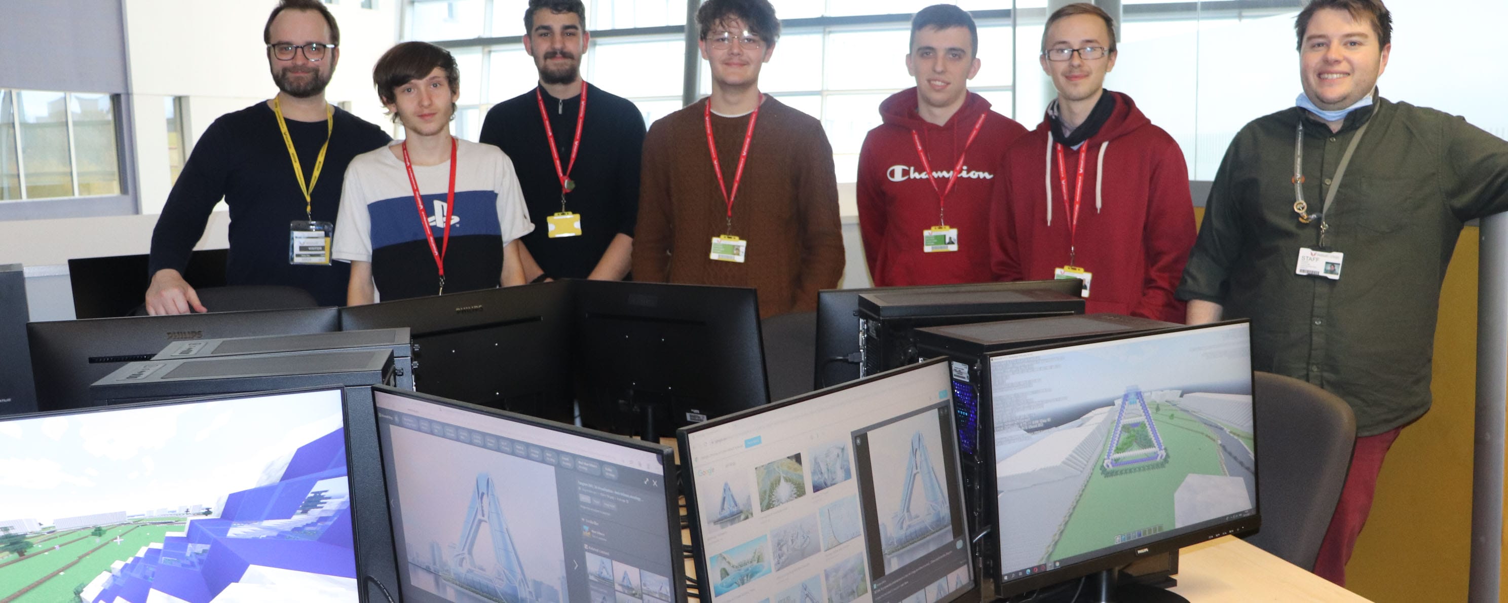 group shot of students posing behind pc screens showing design work