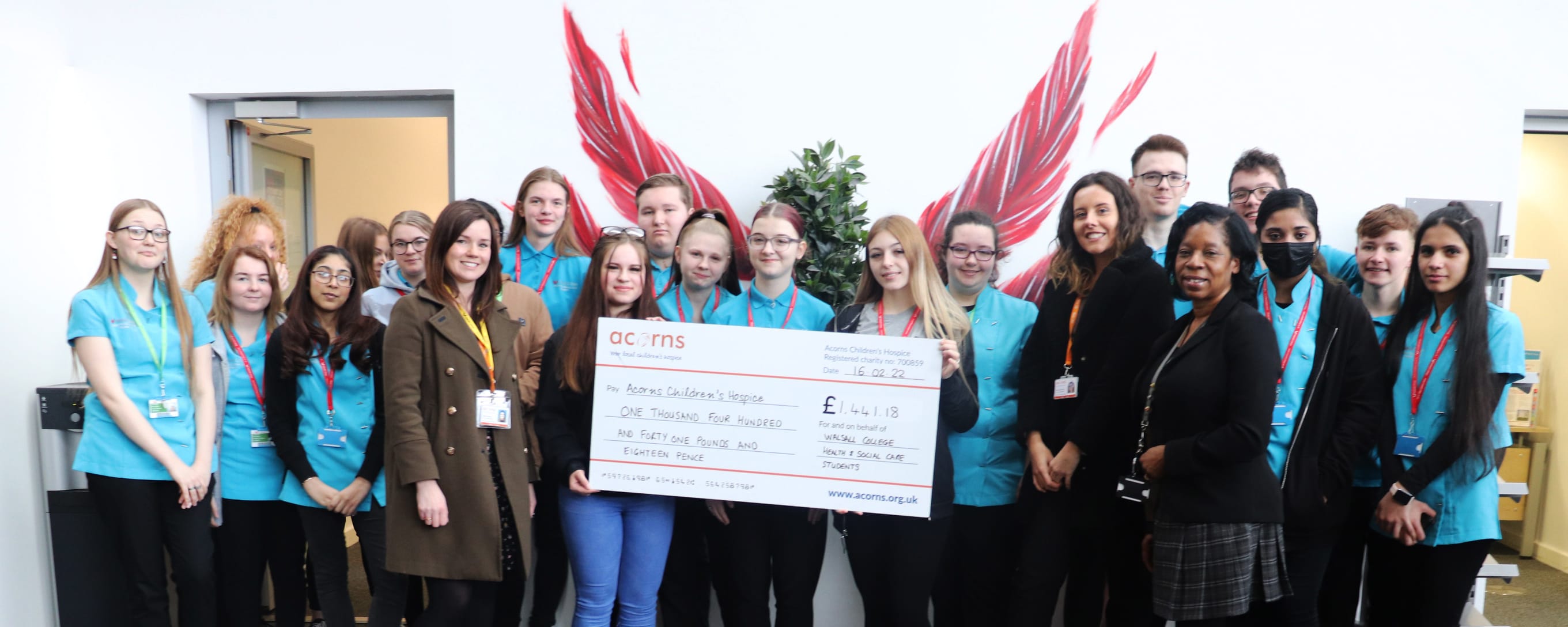 group shot of students presenting cheque to Acorns Hospice representatives facing