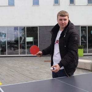 student with ping pong ball and hat about to serve