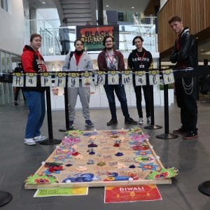 supported learning students in front of decorative Happy Diwali sign