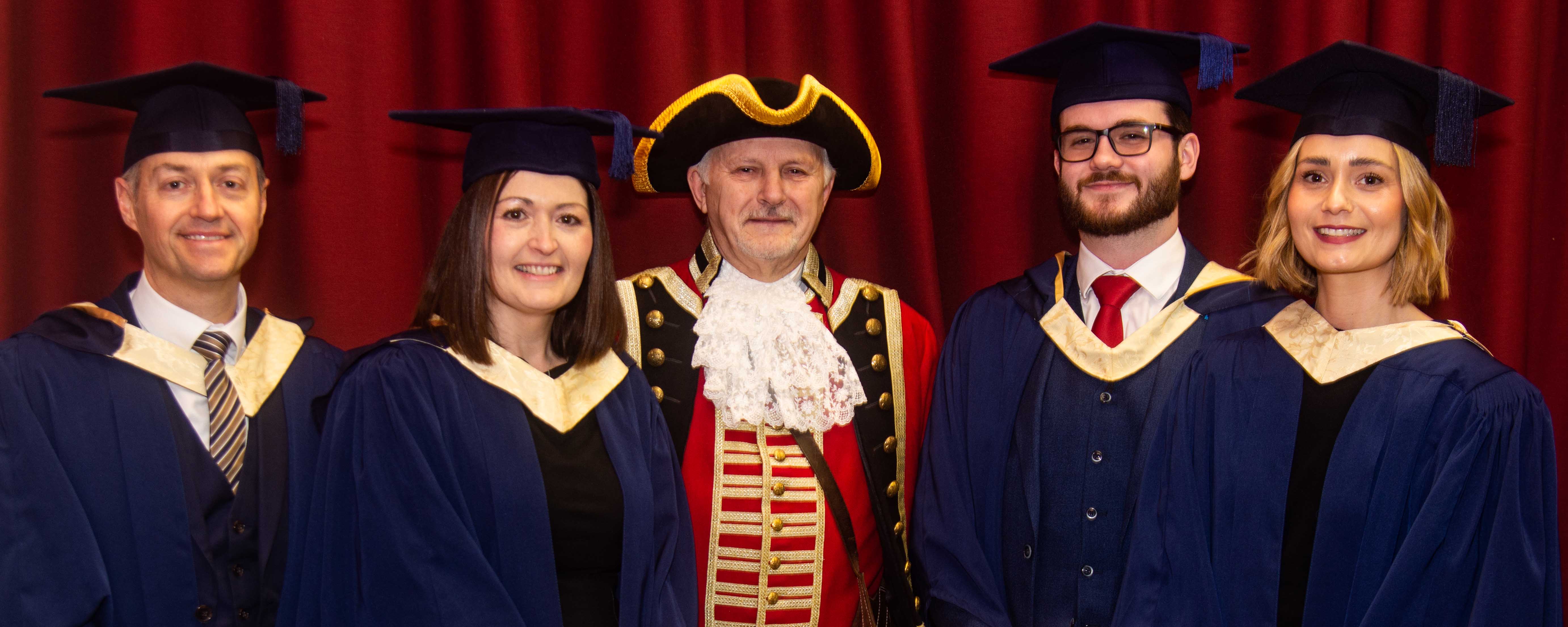 college staff celebrate graduation from teacher education qualification facing