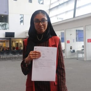 female student holding up results slip facing