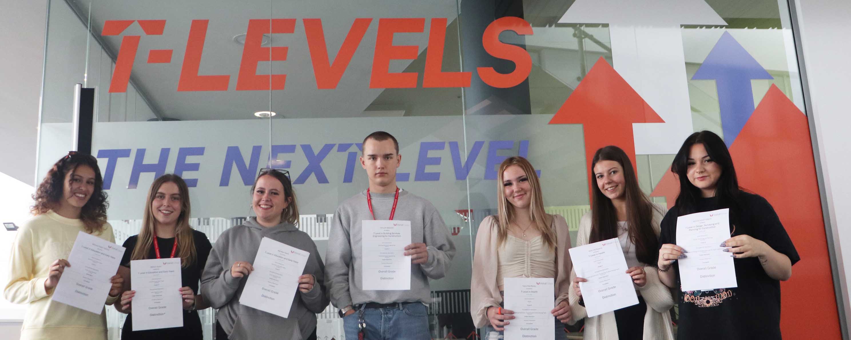 T Level students pose in a line with results slips facing