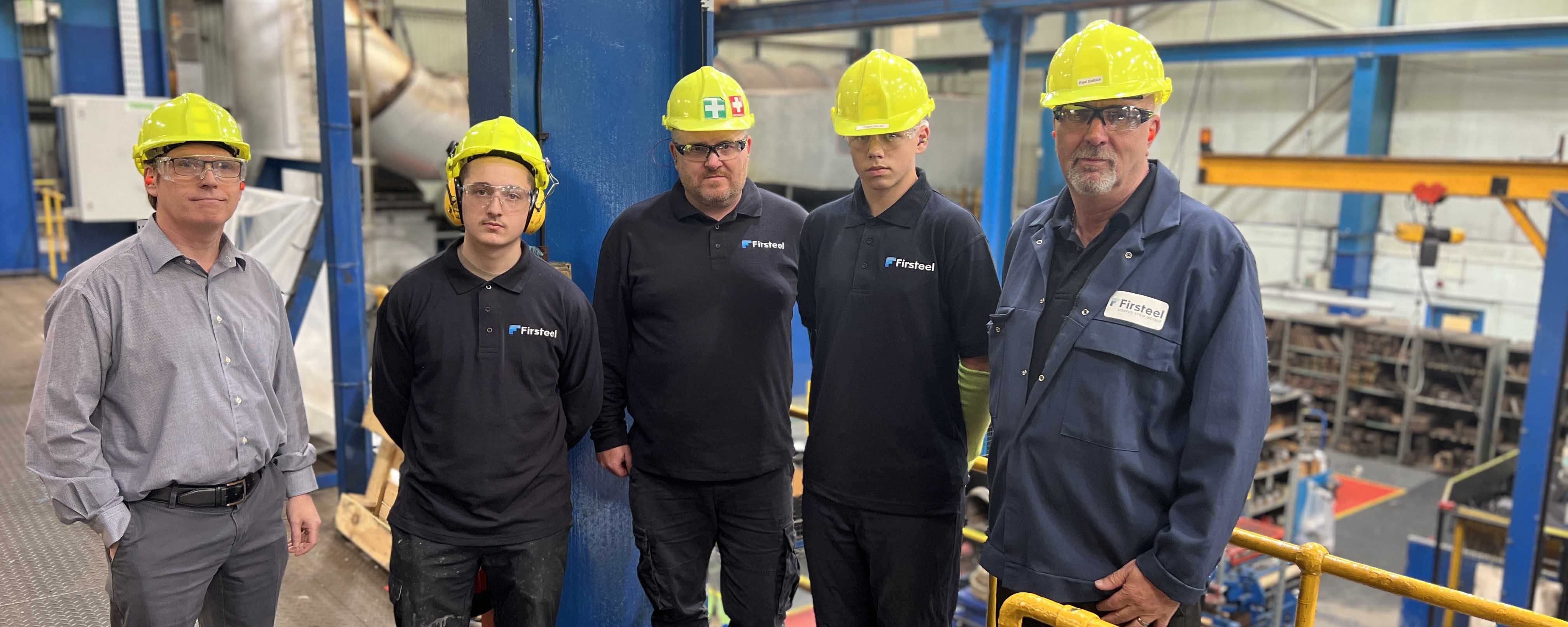 group shot of male apprentices on shopfloor with managers facing