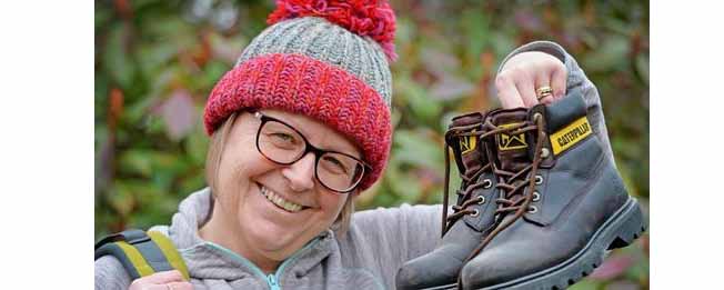 woman holding up walking boots facing