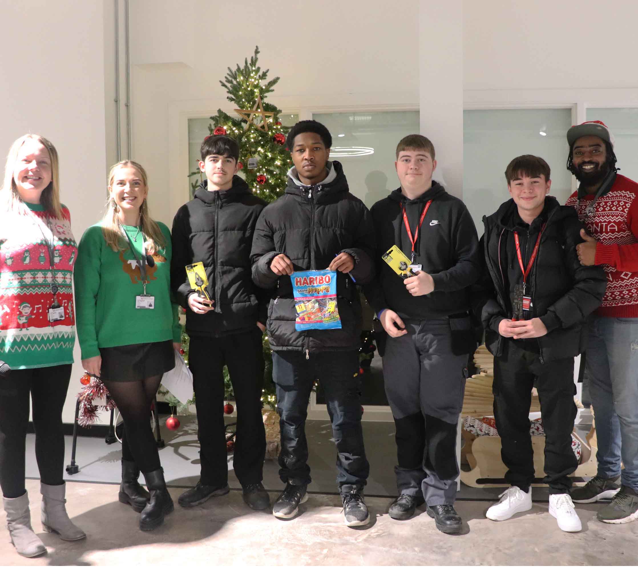 staff and students pose with their competition prizes in front of tree