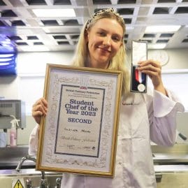 female student chef poses with certificate and medal facing