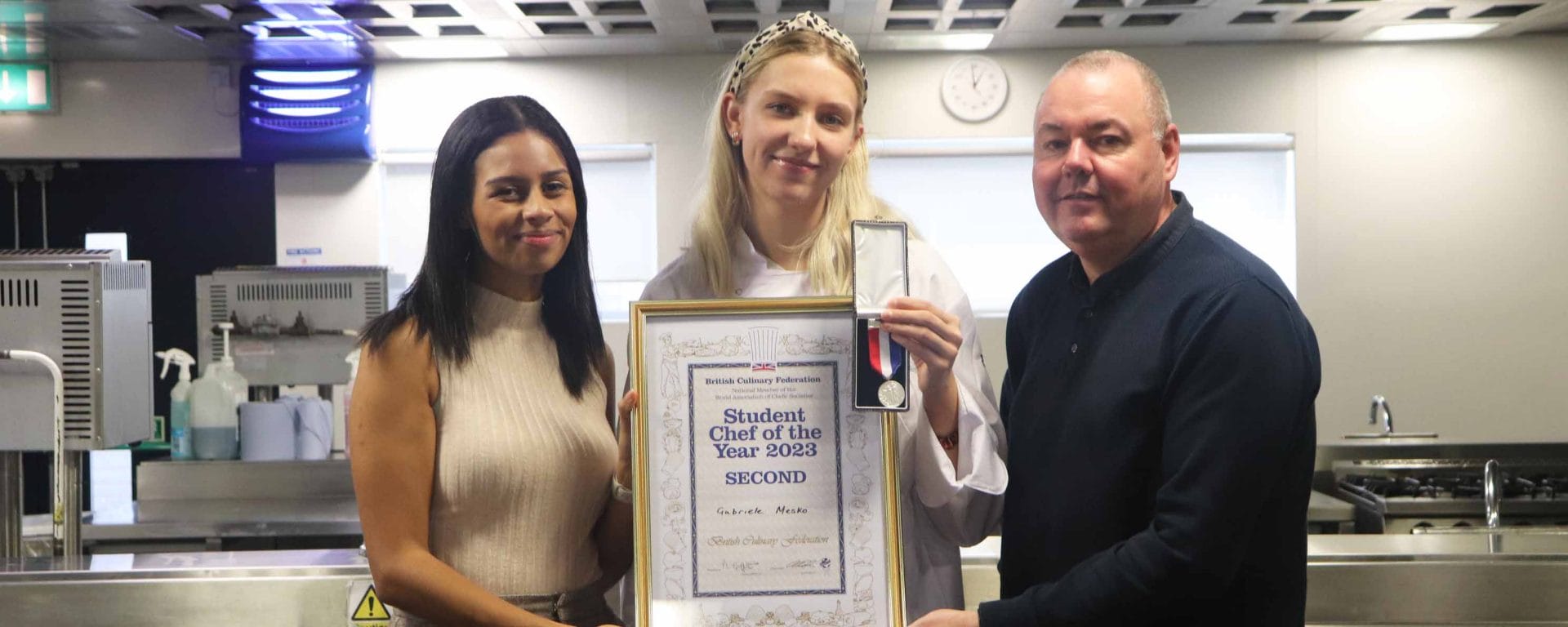 hospitality student posing with award next to two lecturers