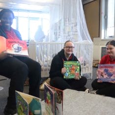 female student trio pose with Christmas stories facing