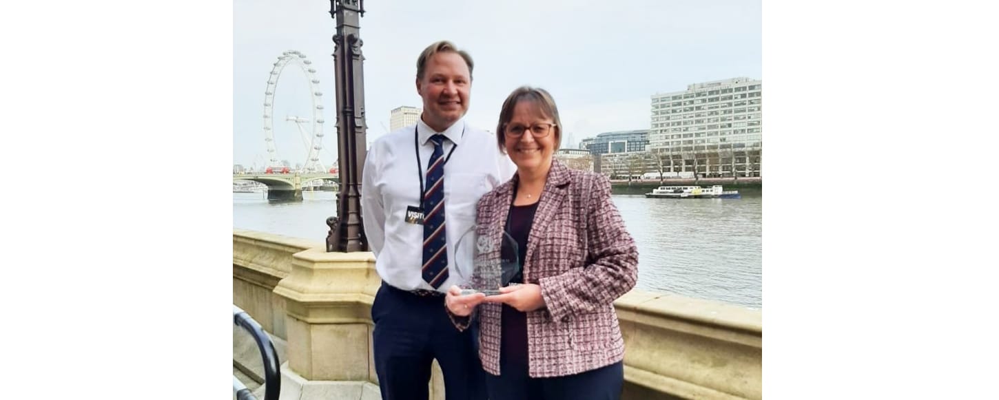 female holding award with male colleague facing