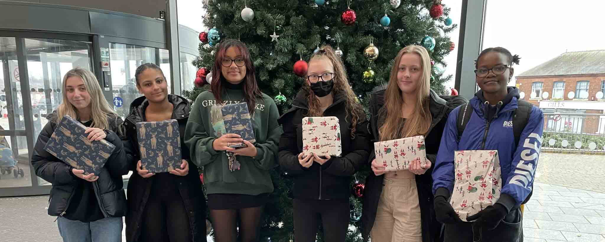 students holding gifts by tree facing