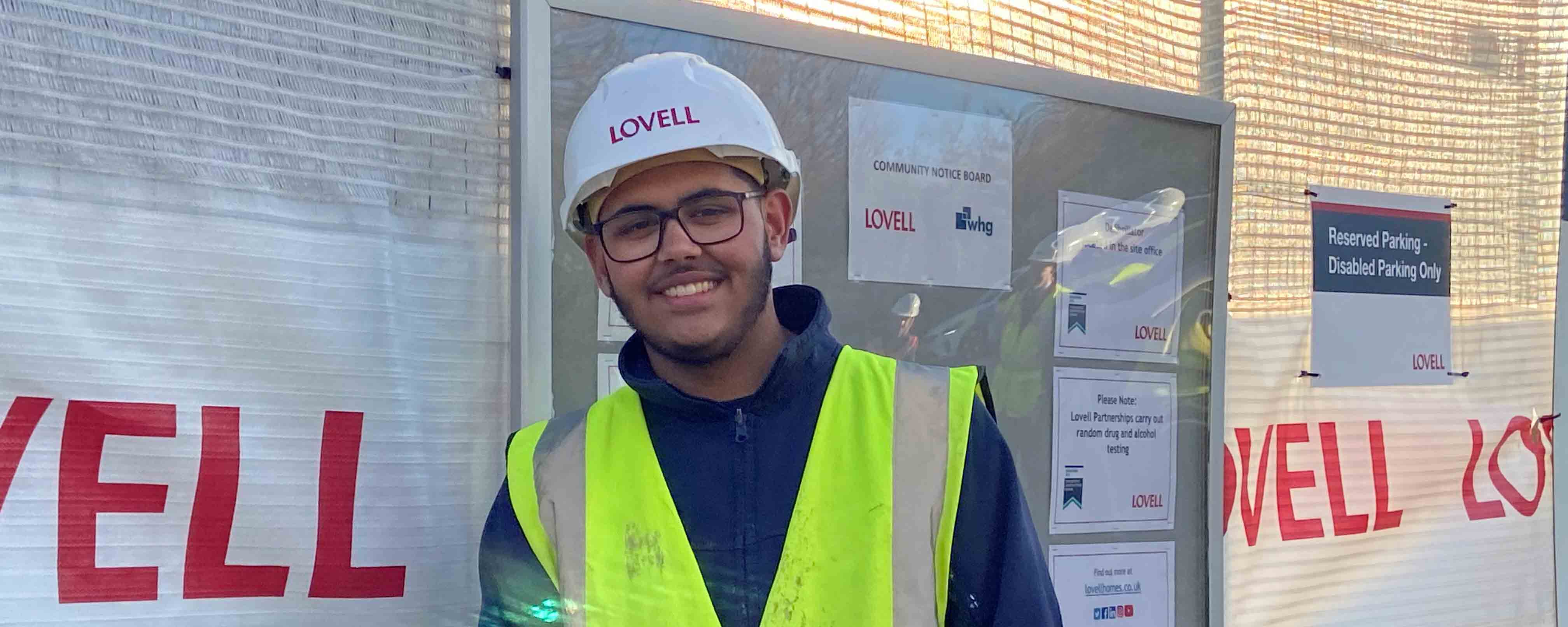 male student in hard hat on building site facing