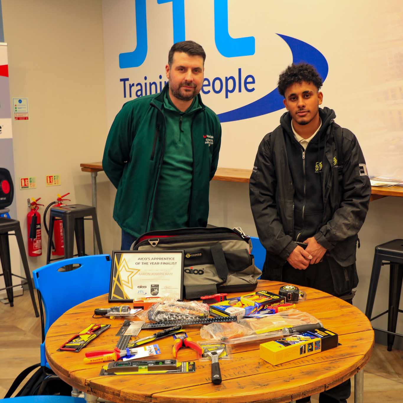 male apprentice with lecturer pose behind toolkit accessories on a table facing