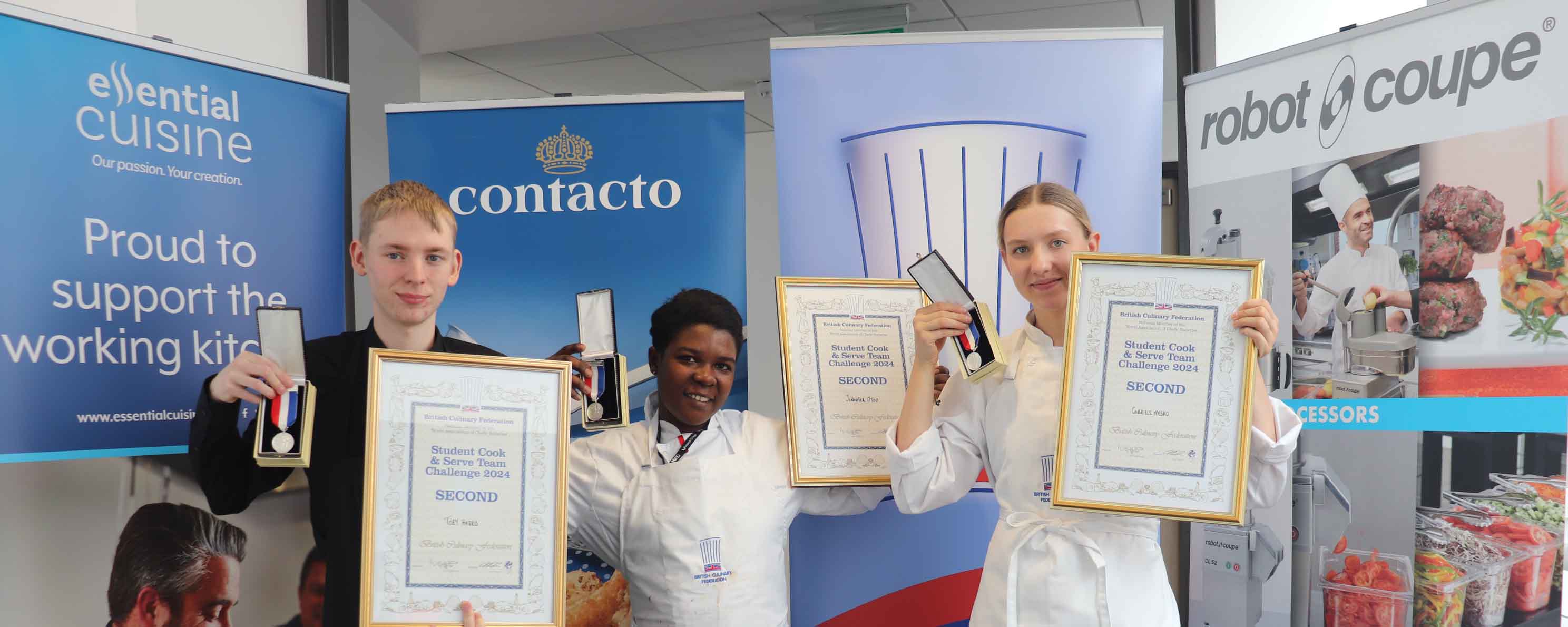 student trio holding up awards in front of banners facing