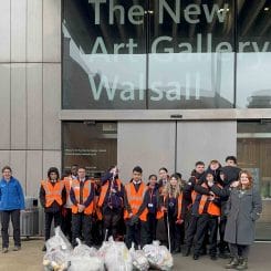 group shot of students in hi-vis jackets with bags of collected litter