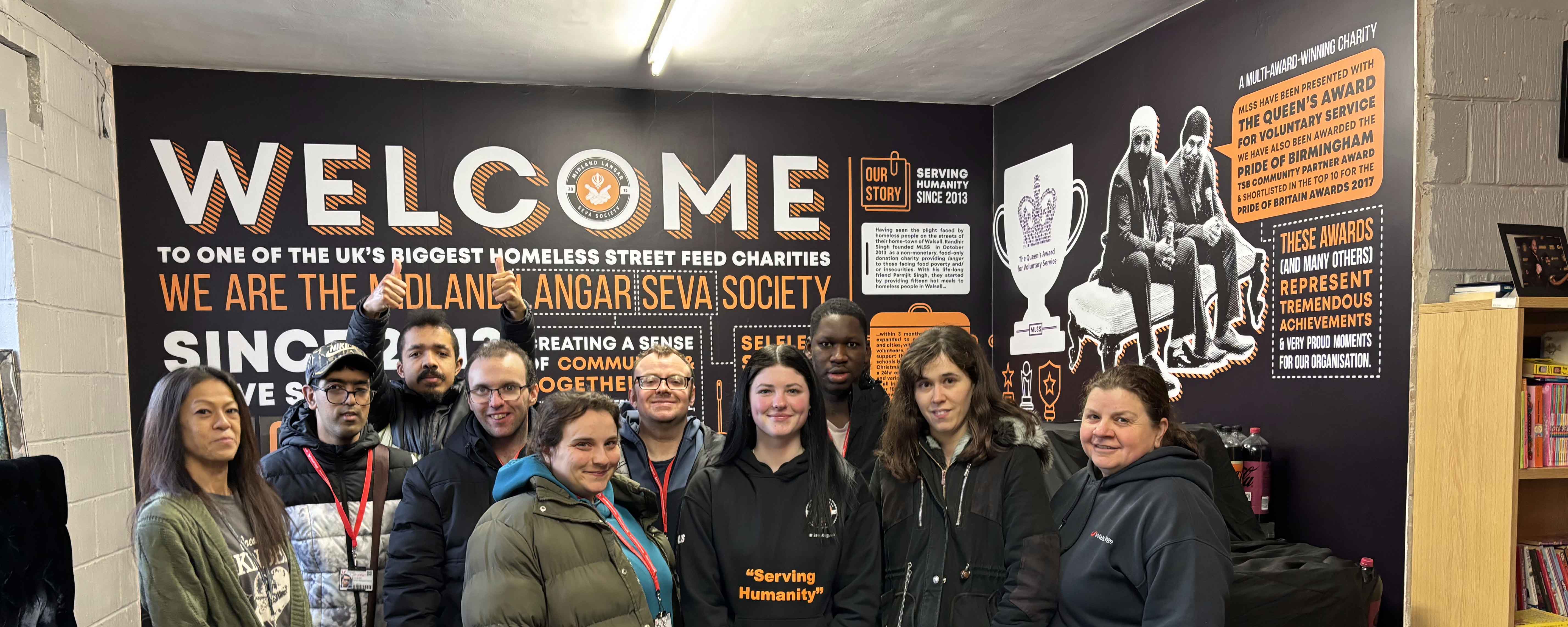 student group shot facing in front of charity signage