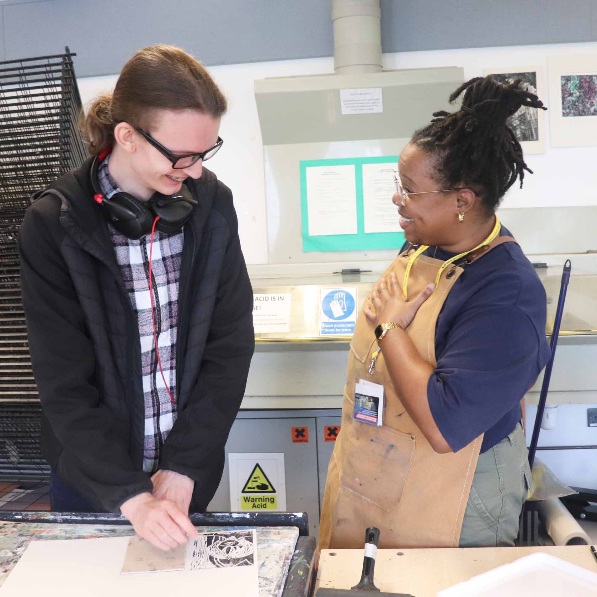artist speaking to student creating lino print