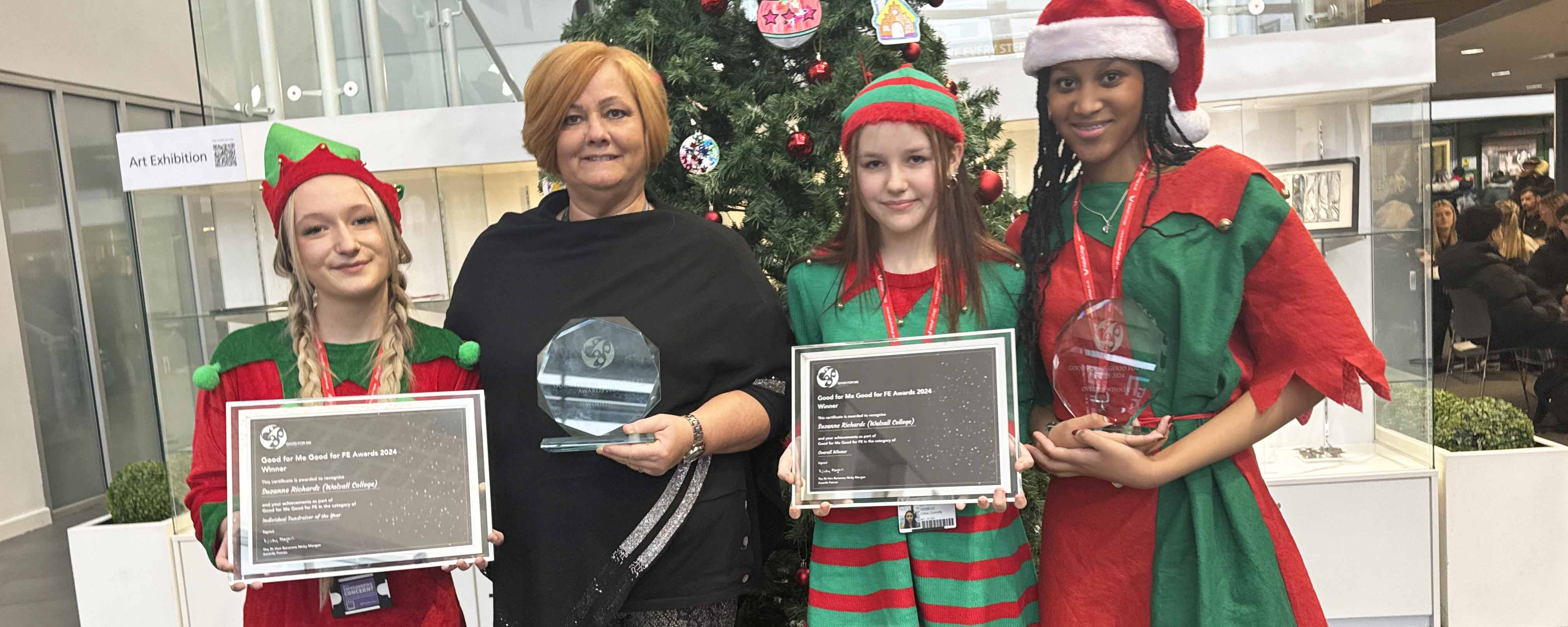 female lecturer and three female students pose with awards in front of Christmas tree