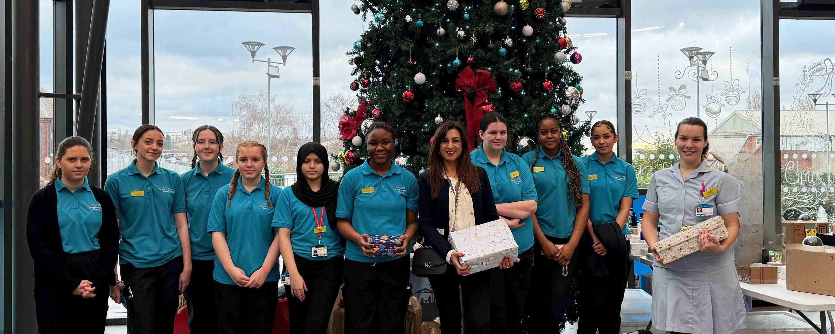 students holding gifts in front of tree