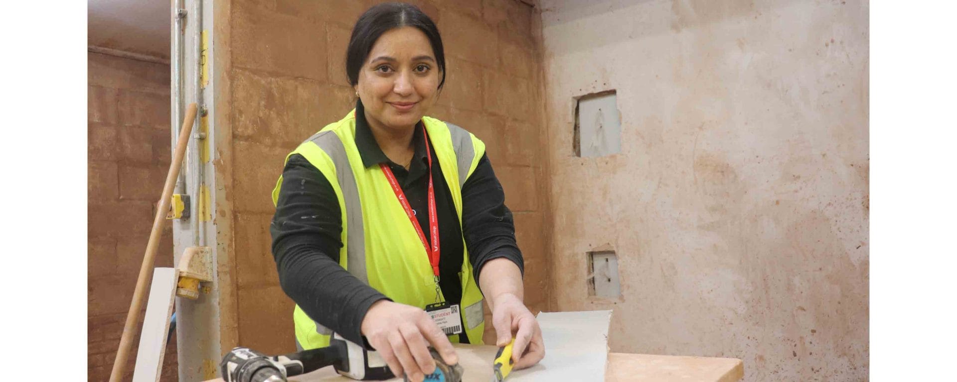 female with chisel in hand cutting plaster board on workbench facing