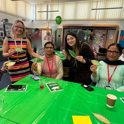 event guests pose with paper green leaf messages