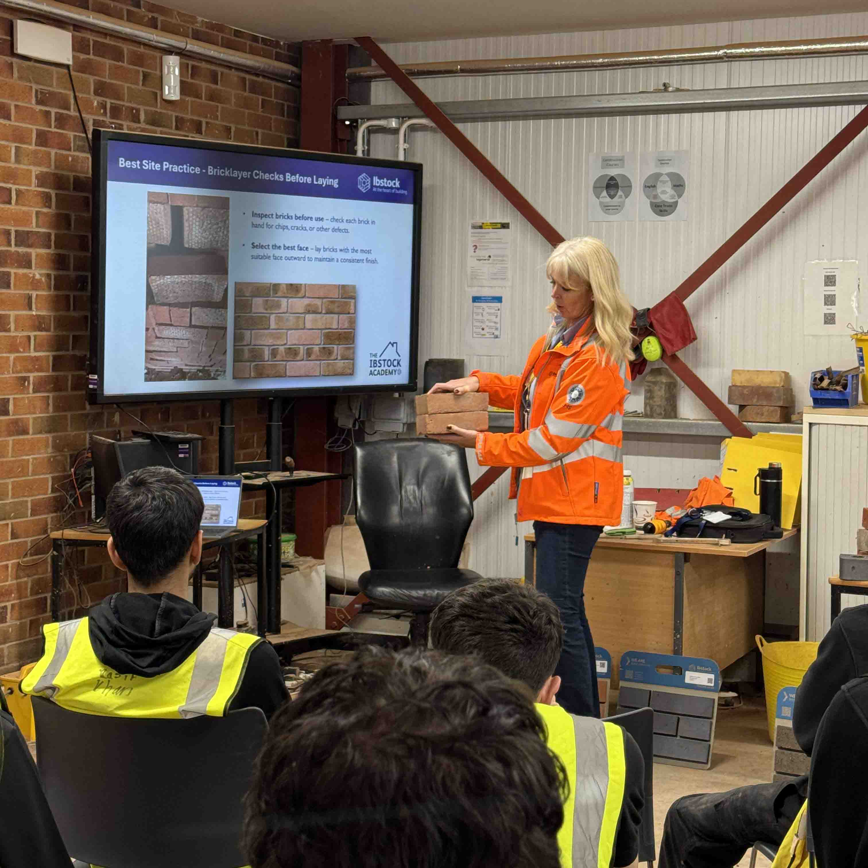 female employer with bricks in hand addressing student group