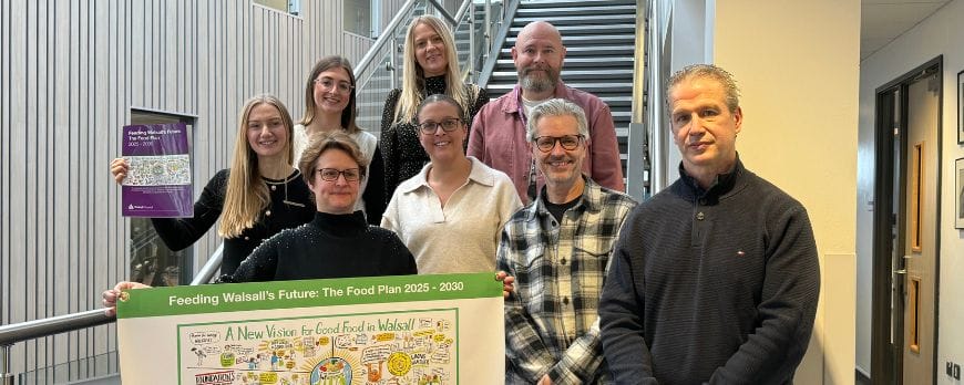 group of people pose with a document plan and mindmap diagram