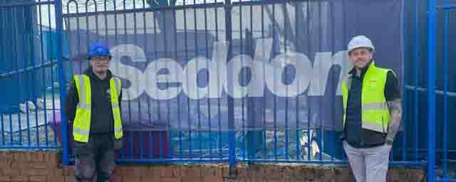 employer and student pose by company sign